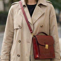 The Scribe mini briefcase worn crossbody over a trench coat, showing its size