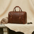 The Voyager full-grain leather duffle — top handle and brass zip detail close-up