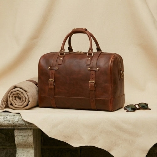 The Voyager full-grain leather duffle — top handle and brass zip detail close-up