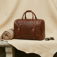 The Voyager full-grain leather duffle — top handle and brass zip detail close-up