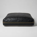 The Haven black leather dog bed, front view showing brass zipper and stitching