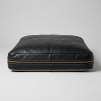 The Haven black leather dog bed, front view showing brass zipper and stitching