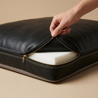 Close up of hand unzipping The Haven black leather dog bed cover
