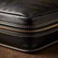 Macro detail of black full-grain leather grain texture and stitching on The Haven dog bed