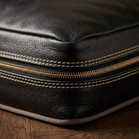 Macro detail of black full-grain leather grain texture and stitching on The Haven dog bed