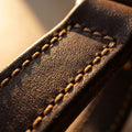 Macro detail of full-grain leather texture and hand-stitching on the dog harness strap