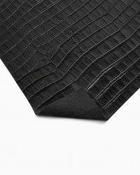 Close-up of black crocodile-embossed cowhide leather with a polished finish and subtle sheen