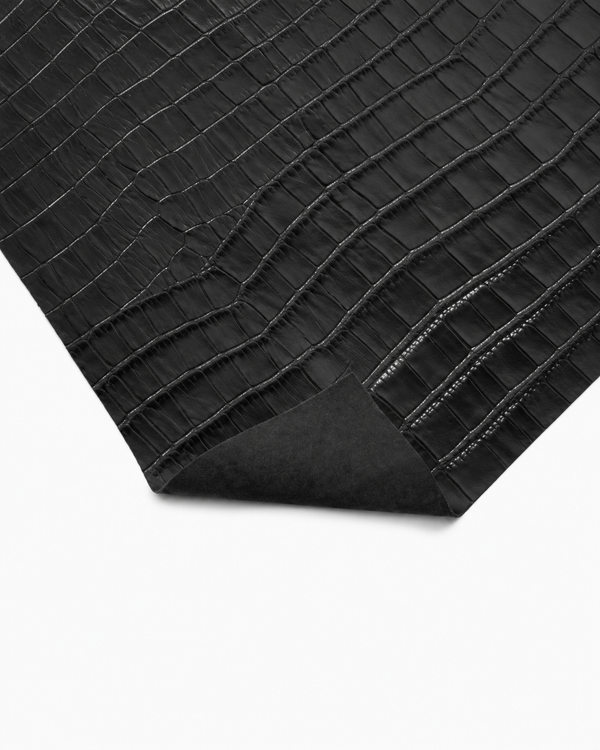Close-up of black crocodile-embossed cowhide leather with a polished finish and subtle sheen